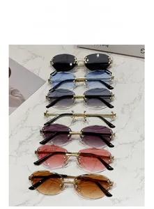 Flat lay of rimless oval sunglasses in seven colors with gold frames on marble surface
