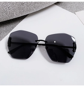 Close-up of frameless oversized sunglasses with grey gradient geometric cut-edge lenses