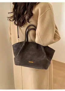 Detail of vintage large capacity dark brown tote bag with matte leather texture on a model