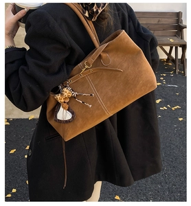 Detail of vintage brown suede tote bag with leopard bow charm and contrast white stitching