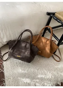 Detail of vintage suede bucket tote bags in dark coffee and camel colors for winter