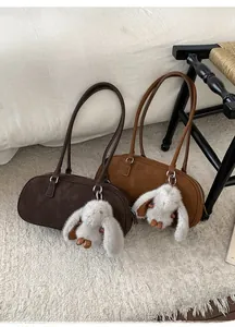 Detail of vintage suede pillow bags in brown and tan with plush bunny charms