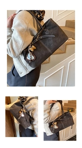 Detail of dark brown leather tote bag with contrast stitching and leopard heart charm