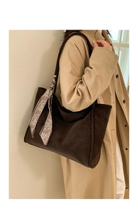 Detail of coffee brown tote bag with silk scarf on handle worn with a trench coat
