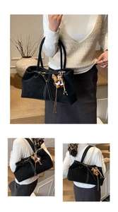 Detail of black suede tote bag with white contrast stitching and leopard print charm