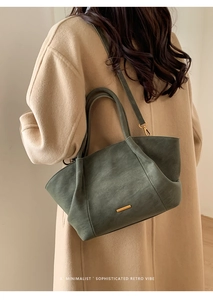 Detailed view of a dark green retro tote bag with golden metal buckle on beige wool coat