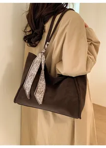 Brown vintage tote bag with patterned silk scarf accessory worn on the shoulder