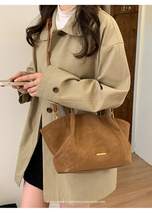 Brown suede tote bag styled with a beige trench coat for a retro minimalist look