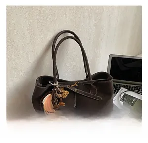 Detail showing deep brown tote bag with white stitching and leopard heart pendant