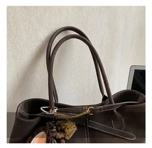 Detail of dark brown suede tote bag with contrast stitching and leopard print pendant