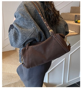 Detail of dark brown matte leather shoulder bag with fine stitching and golden buckle