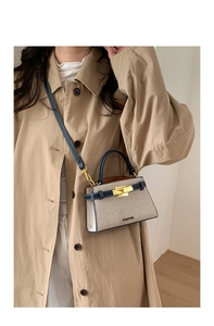 Detail view of a beige canvas and navy leather mini crossbody bag on a khaki coat