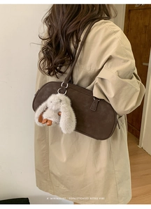 Detail of retro dark brown shoulder bag with a cute white plush bunny charm on the side