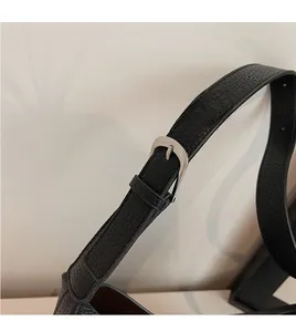 Detail of adjustable black pebble leather strap with silver metallic buckle on bag