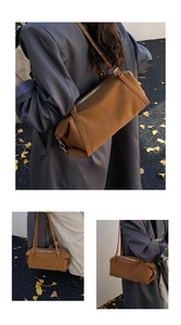 Close-up of brown leather shoulder bag with gold zipper detail and autumn foliage background