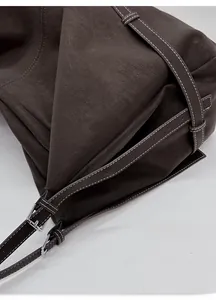 Detail of adjustable strap with metal buckle and contrast stitching on coffee tote bag