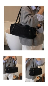 Detail of black Boston bag with adjustable eyelet shoulder straps and gold hardware