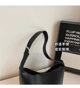 Detail of black lychee-textured bucket bag with adjustable strap and silver buckle