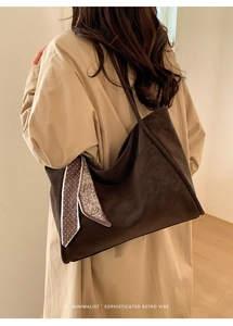 Detail of retro dark brown tote bag with polka dot scarf accent on model shoulder