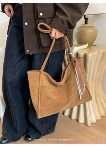 Close-up of vintage brown leather tote bag with a polka dot silk scarf on handle