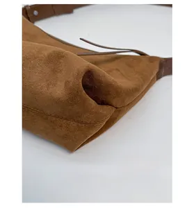 Detail of reinforced bottom corners and stitched seams on a brown suede handbag
