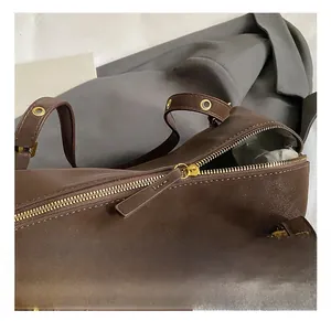 Close-up of retro brown shoulder bag showing gold metal zipper and eyelet hardware