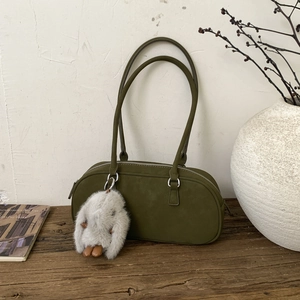 Retro army green suede pillow bag with plush rabbit charm on a rustic wooden table