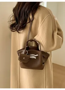 Close-up of brown bucket bag with lychee grain texture and a mini coin purse charm