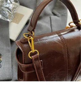 Close-up of golden metal hooks and retro texture on brown faux leather shoulder bag