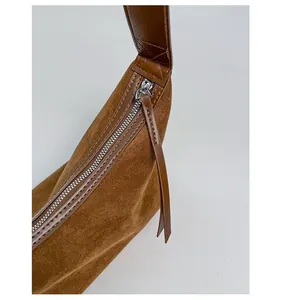 Detailed macro of smooth silver zipper hardware on a premium brown suede shoulder bag