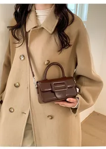 Detail of vintage brown leather handbag with large square buckle and textured finish