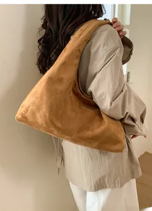 Détail d'un grand sac hobo en daim marron porté à l'épaule pour un look vintage chic