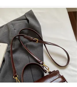Detail of adjustable shoulder strap with golden metal hooks on dark brown retro bag