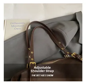 Detail of adjustable strap and golden hardware on dark brown leather tote bag
