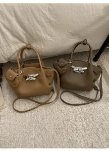 Detail of pleated bucket bag with bow metal lock and mini side pouch accessory