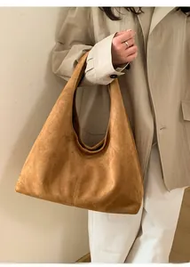 Texture détaillée du sac hobo en daim marron avec large bandoulière porté par un mannequin