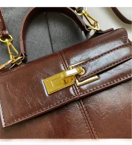 Detailed macro view of gold metal rotating lock on deep brown oil-wax leather handbag