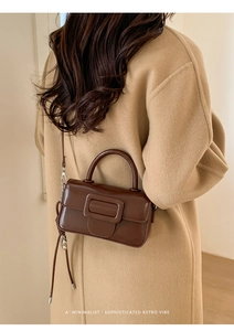 Brown vintage square handbag with oversized buckle shown on a coat for size scale