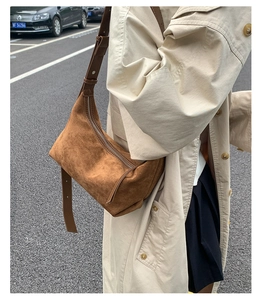 Sac Hobo en daim marron foncé porté à l'épaule dans un style de rue décontracté