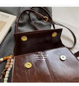 Detail view of the strong magnetic buckle and polished leather texture on coffee bag