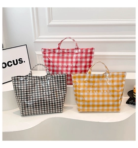 Three plaid PVC tote bags in red, black, and yellow displayed on a white stand