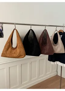 Détails de sacs cabas en daim en couleurs caramel, noir, café et beige sur un présentoir