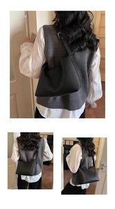 Close-up of black lychee grain leather shoulder bag with wide strap and hobo style texture