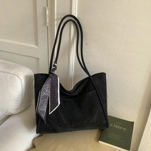 Close-up of black matte tote bag with front pocket and elegant patterned silk scarf detail