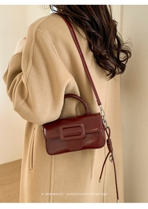 Deep burgundy retro square handbag shown styled with a classic camel coat on model