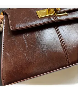 Detail of vintage dark brown faux leather bag featuring textured finish and gold metal lock