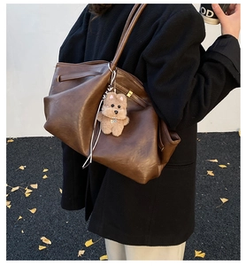 Brown vintage faux leather tote bag with plush bear charm and adjustable side straps