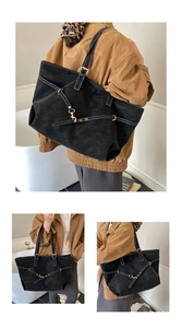 Detail view of large black suede tote bag with contrast white stitching and gold buckles