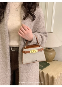 Detail of canvas handbag with brown leather trim and embroidery in a cozy home setting