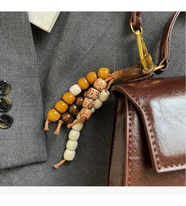 Detail of bohemian wood bead charm with gold clasp hanging on a brown leather bag